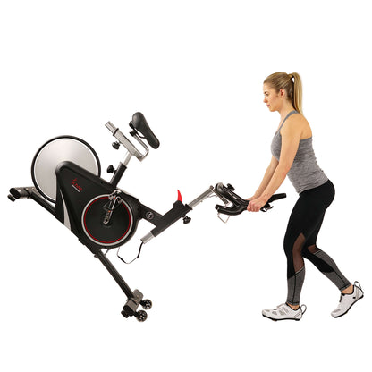 Woman moving Sunny Health & Fitness recumbent bike with enhanced Bluetooth connectivity and adjustable seat lever.