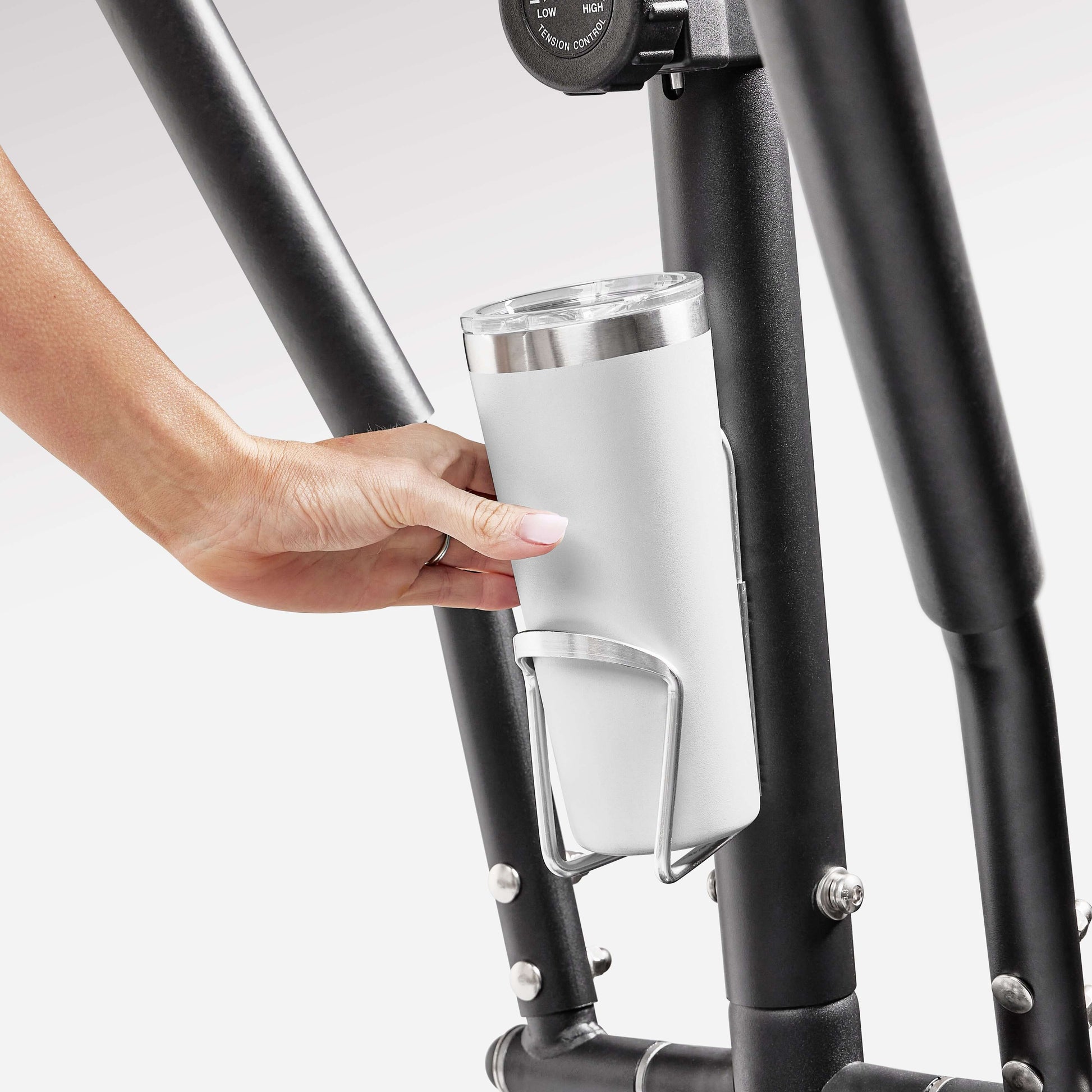 Hand placing a tumbler in the bottle holder of Sunny Health & Fitness Premium Cardio Climber SF-E3919.